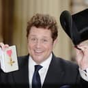 British actor and singer Michael Ball, poses for a photograph with his Officer of the Order of the British Empire (OBE) medal, after being presented with it during an investiture ceremony at Buckingham Palace in London on January 29, 2016.