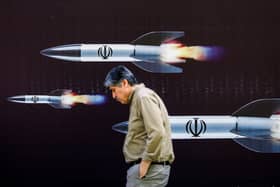 A man walks past a banner depicting missiles along a street in Tehran (Photo: -/AFP via Getty Images)