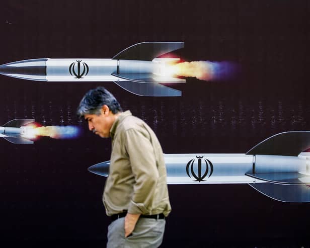A man walks past a banner depicting missiles along a street in Tehran (Photo: -/AFP via Getty Images)