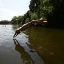 A swimmer diving into the water at the mixed bathing ponds in Hampstead Heath, London