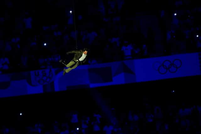 Tom Cruise descends from the stadium roof during the closing ceremony