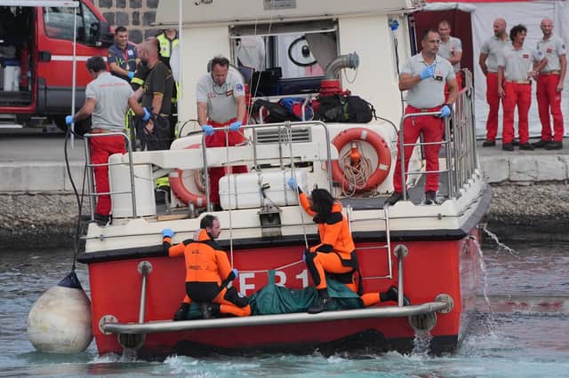 A body bag is brought ashore at the harbour in Porticello by rescue workers searching for the six tourists missing after the luxury yacht Bayesian sank in a storm on Monday whilst moored around half a mile off the Sicilian coast