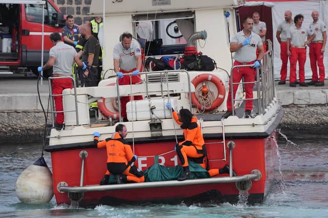 A body bag is brought ashore at the harbour in Porticello by rescue workers searching for the six tourists missing after the luxury yacht Bayesian sank in a storm on Monday whilst moored around half a mile off the Sicilian coast