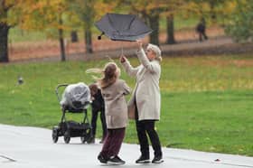 A woman's umbrella is caught by a gust of wind during a rain shower, in Greenwich Park, London
