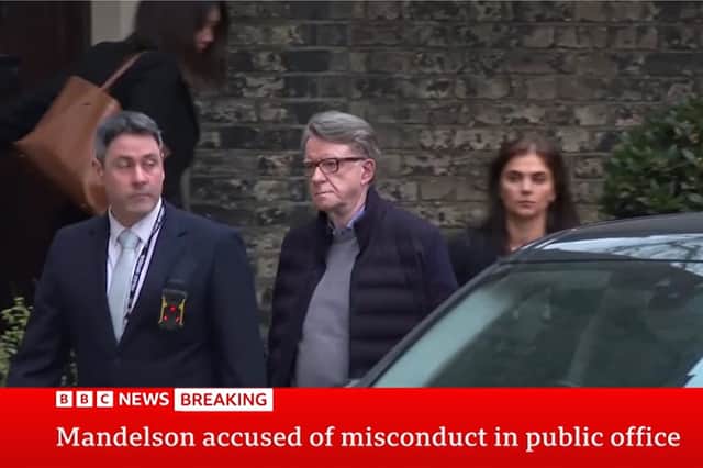 Plain clothed police officer leading Lord Peter Mandelson out of a house in London