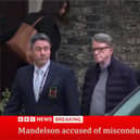Plain clothed police officer leading Lord Peter Mandelson out of a house in London
