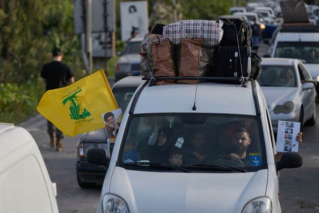 A displaced family ride in a car carrying a Hezbollah flag along with a portrait of late Hezbollah leader Sayyed Hassan Nasrallah, as they return to their village following a ceasefire between Hezbollah and Israel, in Qasmiyeh near the city of Tyre, south Lebanon