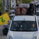 A displaced family ride in a car carrying a Hezbollah flag along with a portrait of late Hezbollah leader Sayyed Hassan Nasrallah, as they return to their village following a ceasefire between Hezbollah and Israel, in Qasmiyeh near the city of Tyre, south Lebanon