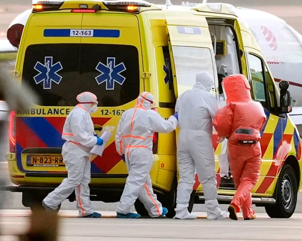 Medics escort a patient, second right, evacuated from the MV Hondius cruise ship with suspected hantavirus infection, to an ambulance after being flown to Schiphol airport, Amsterdam, Netherlands