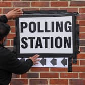 A man displays a polling station sign in Greenwich in London during the local elections on May 7, 2026