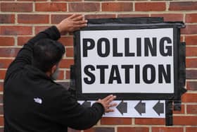 A man displays a polling station sign in Greenwich in London during the local elections on May 7, 2026