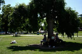 People sit in shade as one person lies in the sun in Stratford-upon-Avon in Warwickshire