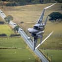 A US Air Force F-15E Strike Eagle banks dramatically over a road during low-level training through the Mach Loop in Wales.