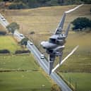 A US Air Force F-15E Strike Eagle banks dramatically over a road during low-level training through the Mach Loop in Wales.