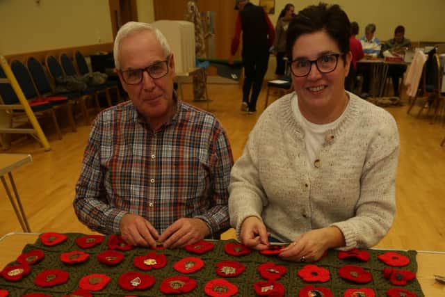Richard Black, who has collected over 100 military cap badges, and Carol Robinson, sew the badges onto hand made poppies and on to a crocheted blanket. AN442726