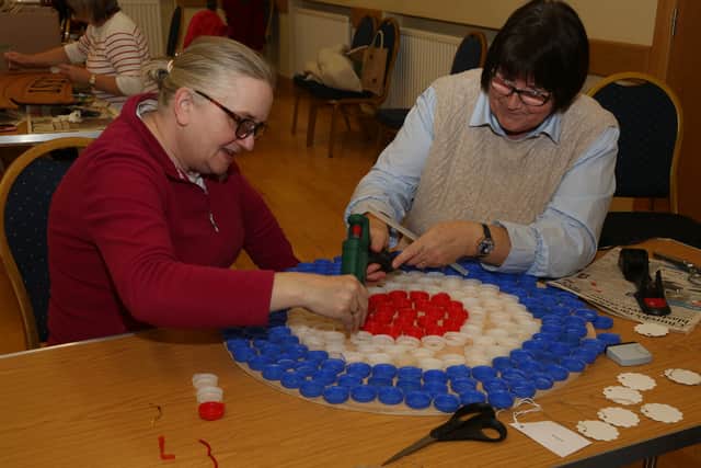 Ann Crawford and June McElhill glueing coloured bottle tops to plywood to form an RAF roundel for the Festival of Poppies. AN443026