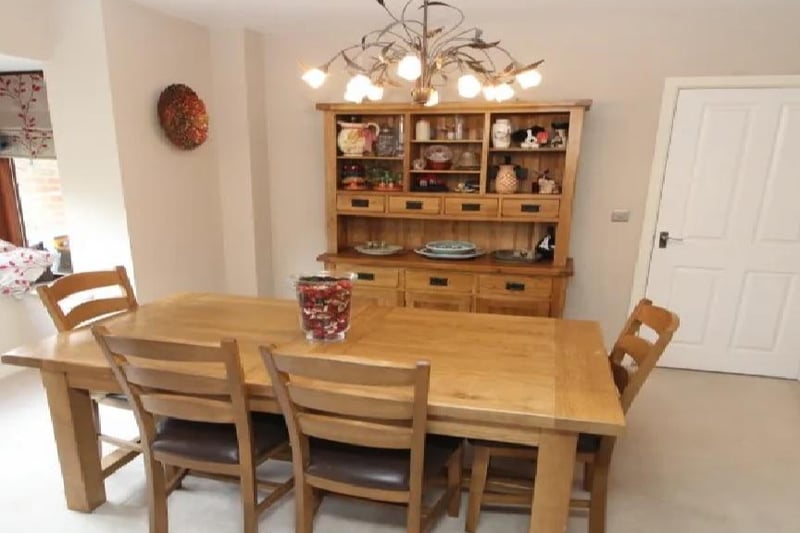This homely dining room has carpeted flooring, a radiator and could comfortably sit a family.