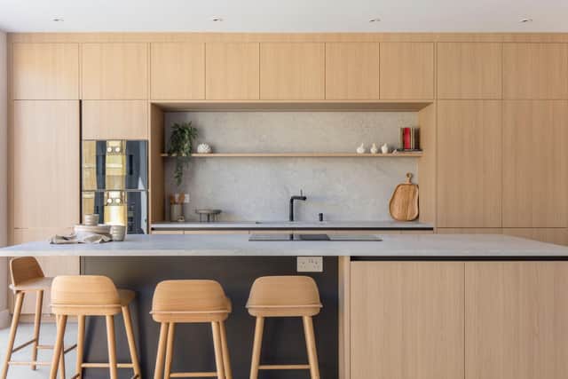 Streamlined oak cabinets, an oak island and wood-toned stools add sophistication to a Nordic-inspired kitchen.