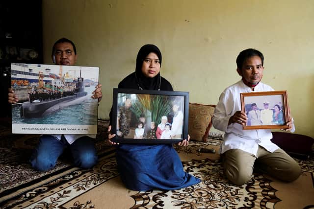 Family members hold photographs of Marine Colonel Harry Setiawan - the commander of the Navy's KRI Nanggala (402) submarine. (Rayi Gigih/AFP via Getty Images)
