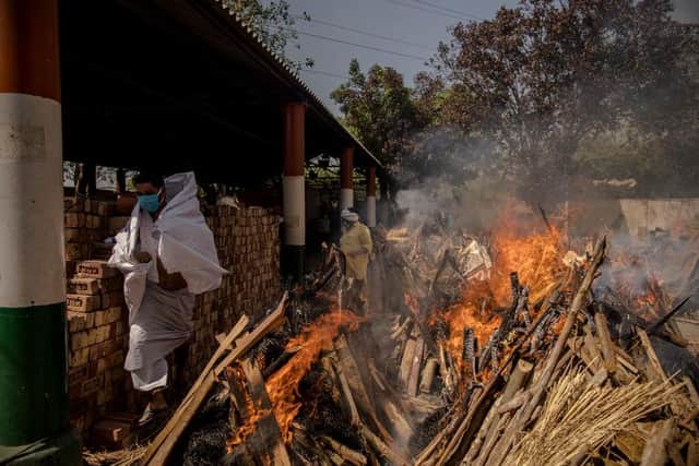 A priest (L) who helps performing last rites, runs to avoid the heat from the multiple burning funeral pyres of patients who died of the Covid-19 coronavirus disease at a crematorium on April 24, 2021 in New Delhi, India.