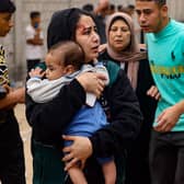 An injured woman carries a baby in the aftermath of Israeli bombing in Rafah in the southern Gaza Strip. (Picture: Mohammed Abed/AFP via Getty Images)