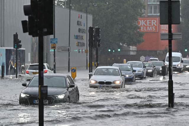 Cars drive through deep water on a flooded road in The Nine Elms district of London on July 25, 2021 during heavy rain (AFP/Getty)