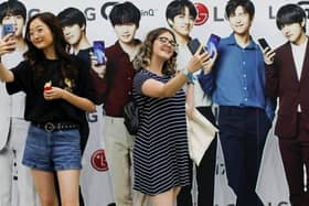 Fans pose for selfies with life-size cutouts of their favorite K-pop idols at a promotional event.
