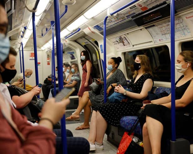 Commuters with facemasks travel on the London Underground in London (Photo by Tolga Akmen / AFP)