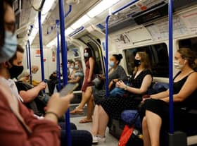 Commuters with facemasks travel on the London Underground in London (Photo by Tolga Akmen / AFP)