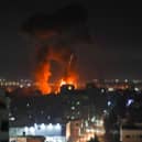 Explosions light-up the night sky above buildings in Gaza City as Israeli forces shell the Palestinian enclave (Photo by MAHMUD HAMS/AFP via Getty Images)