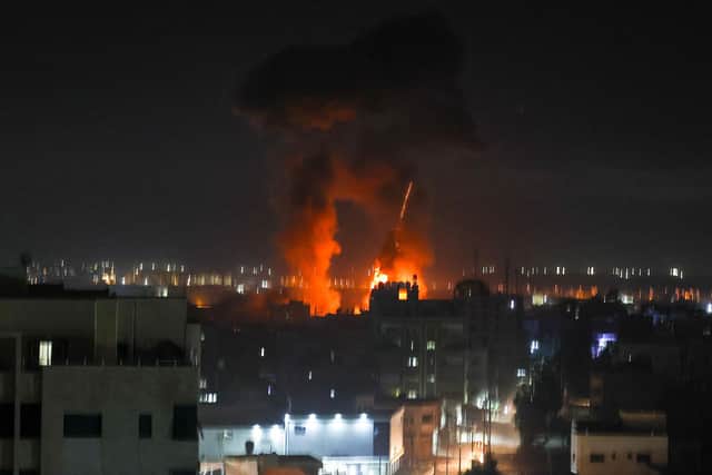 Explosions light-up the night sky above buildings in Gaza City as Israeli forces shell the Palestinian enclave (Photo by MAHMUD HAMS/AFP via Getty Images)