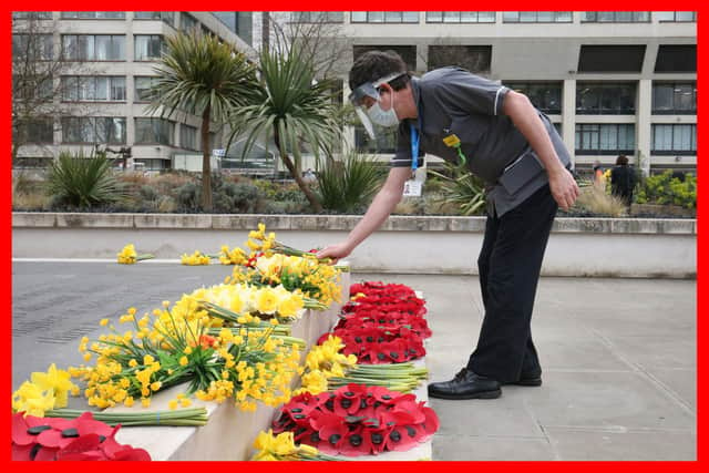 A member of staff places flowers near the statue of Crimean War nurse Mary Seacole during a ceremony to observe a minute's silence at St Thomas' Hospital, central London