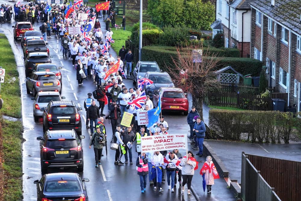   Hundreds of people have marched through the streets of Crowborough in protest at government plans to house up to 600 asylum seekers at a former military site.  