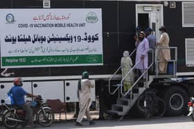People wait for their turn to get a dose of a vaccine against the Covid-19 coronavirus outside a mobile vaccination health unit in Lahore, Pakistan (Photo: ARIF ALI/AFP via Getty Images)