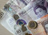 A single pound coin atop an orange £10 note and three purple £20 notes. (Credit:  Tolga Akmen / AFP)