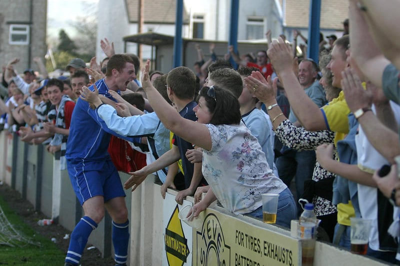 Michael Towey celebrates the 92nd minute winner with fans behind the goal.