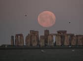 The full moon sets behind Stonehenge in Amesbury, England. (Photo by Finnbarr Webster/Getty Images)