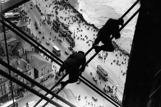 15th August 1934 - Workmen balanced high above the street and the beach on the struts of the town during repair work