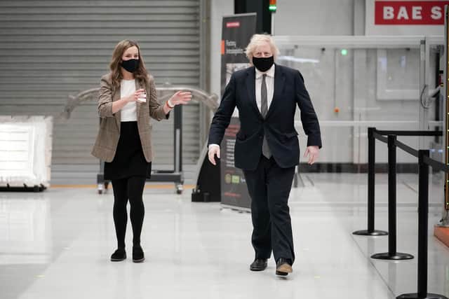 Prime Minister Boris Johnson is escorted by apprentice Laura Langtree during a visit to BAE Systems at Warton Aerodrome in Lancashire, to mark the publication of the Integrated Review and the Defence White Paper. Picture date: Monday March 22, 2021. PA Photo. See PA story DEFENCE Johnson. Photo credit should read: Christopher Furlong/PA Wire