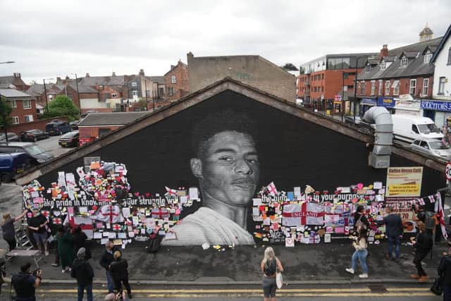 People look at the newly repaired mural of England footballer Marcus Rashford by the artist known as AKSE_P19, after it was defaced by vandals in the aftermath of England's Euros loss.