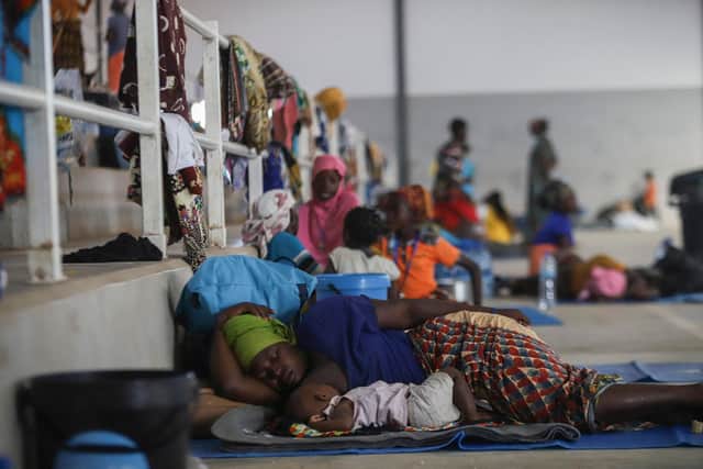 A woman rests with her baby on the ground at the Pemba Sports center that is now a shelter (Getty Images)