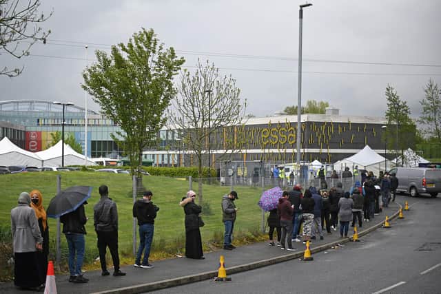 Members of the public queue to receive a Covid-19 vaccine at a temporary vaccination centre at the Essa academy in Bolton (Photo by Oli SCARFF / AFP)