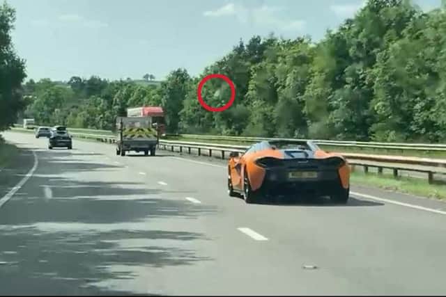 The moment a McLaren supercar had to dodge an empty water bottle (red circle), just averting disaster,  on the A30 just off of the M5 near Exeter (Photo: SWNS)