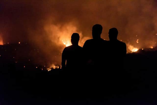 People in the village of Vavatsinia in the Larnaca district of Cyprus watch as the wildfire rages on the nearby hills during the night of 3 July (Picture:  Getty Images)
