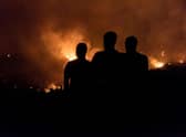 People in the village of Vavatsinia in the Larnaca district of Cyprus watch as the wildfire rages on the nearby hills during the night of 3 July (Picture:  Getty Images)