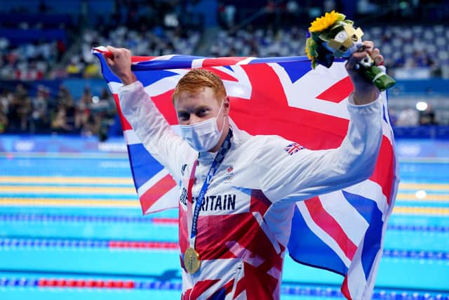 Great Britain's Tom Dean waves the Union flag after celebrating becoming a champion of the pool (PA)