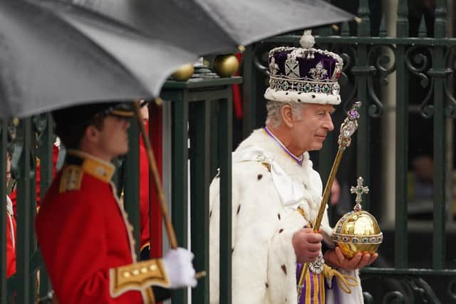 King Charles III, wearing the Imperial State Crown, leaves Westminster Abbey in central London following his coronation ceremony.