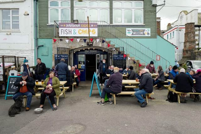 Groups of friends enjoy a drink together at The Front pub on Custom House Quay, on April 12, 2021 in Falmouth (Photo by Hugh Hastings/Getty Images)