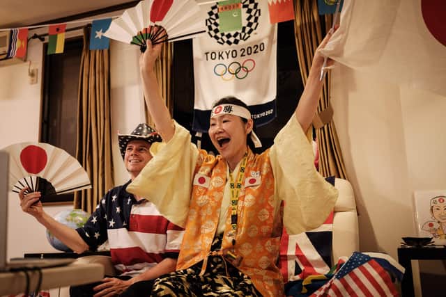 Olympic super-fan Kyoko Ishikawa (R) who has attended every Summer Olympics in the past 30 years and her husband John Sledge (L) react as Japanese athletes appear on TV during the opening ceremony (Photo by Yasuyoshi CHIBA / AFP)