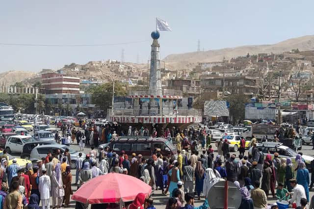 A Taliban flag is seen on a plinth with people gathered around the main city square at Pul-e-Khumri on August 11 after the Taliban captured Pul-e-Khumri, the capital of Baghlan province about 200 kms north of Kabul. (AFP/Getty)